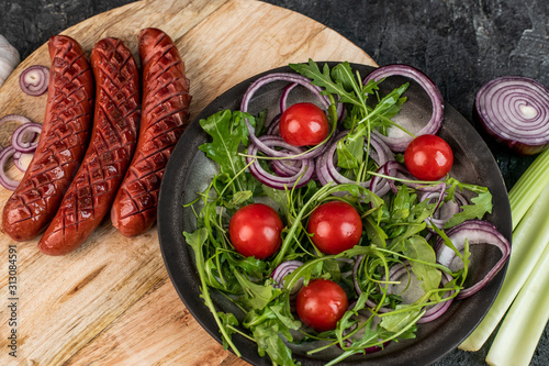 roasted sausages and arugula salad with cherry tomatoes and onions