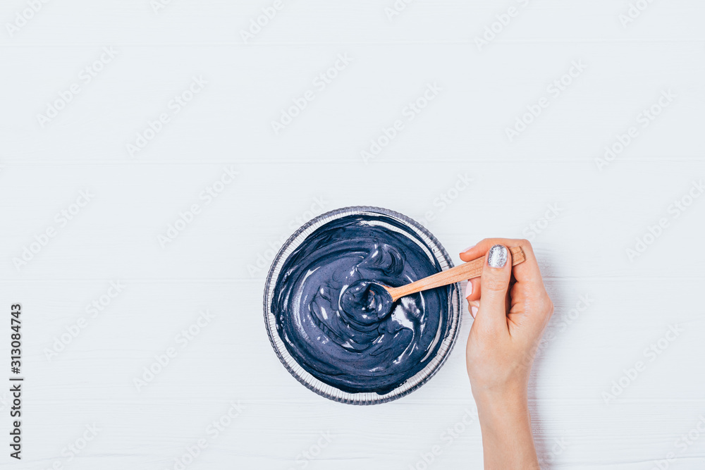 Woman's hand mixing black clay cosmetic mask