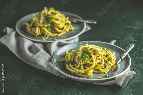 Spaghetti pasta bucatini with pesto sauce and parmesan. Italian traditional perciatelli pasta by genovese pesto sauce  in two gray dishes photo