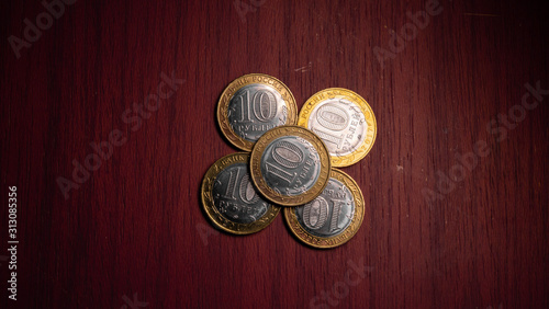 Ten anniversary rubles. Russian jubilee coins. Coins in denominations of ten rubles (10 rub) are folded with a flower, lie on a mahogany table. Concept of business, finance and collecting rare coins. 