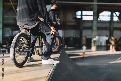 Young males staying with their bikes on the ramp. Unrecognizable BMX riders is performing tricks in indoor skatepark. BMX freestyle. Extreme sport.