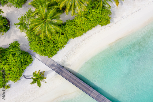 Aerial view of Maldives resort. Beautiful sea and lagoon, palm trees on white sandy beach. Luxury summer vacation background view from drone perspective