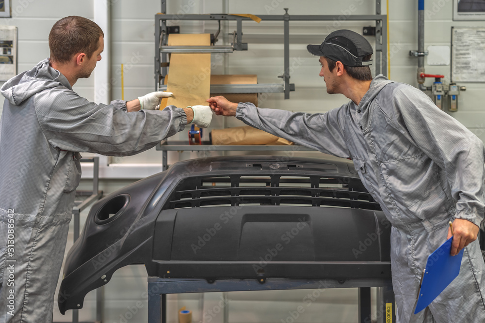 An employee of the paint shop of the automobile plant conducts training on the preparation of bumpers for painting An employee of the paint shop of the automobile plant conducts training on the preparation of bumpers for painting