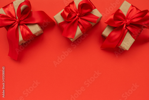 Three gift boxes wrapped on red ribbons on red background. Valentines day or Mothers day celebration concept. Top view. copy space