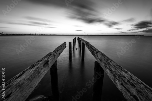 Black and white wooden jetty leading into the sea 