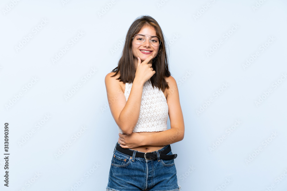 Young woman over isolated blue background with glasses and smiling Young woman over isolated blue background with glasses and smiling