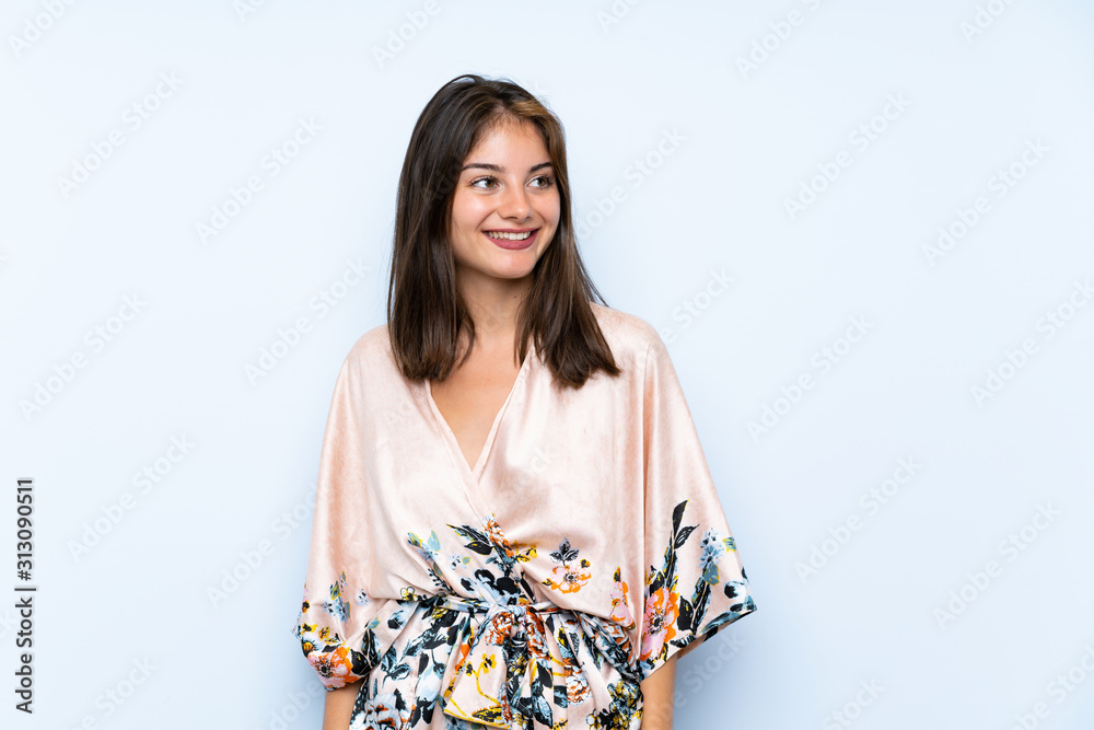 Caucasian girl with kimono over isolated blue background laughing and looking up Caucasian girl with kimono over isolated blue background laughing and looking up