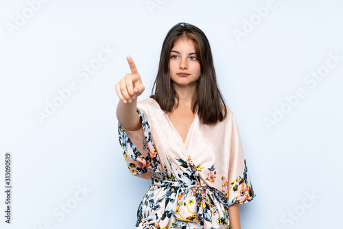 Caucasian girl with kimono over isolated blue background touching on transparent screen