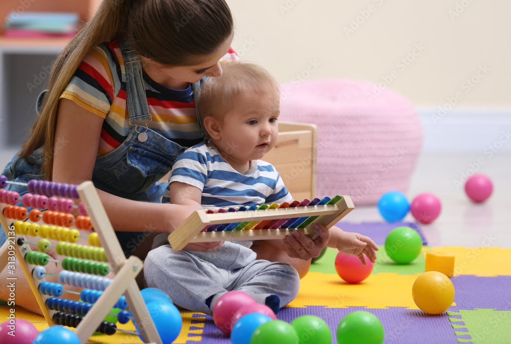 Obraz premium Teen nanny and cute little baby playing with xylophone at home