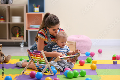 Teen nanny and cute little baby playing with xylophone at home