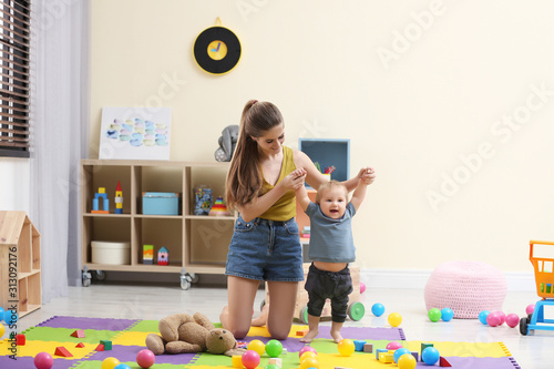 Teen nanny playing with cute little baby at home