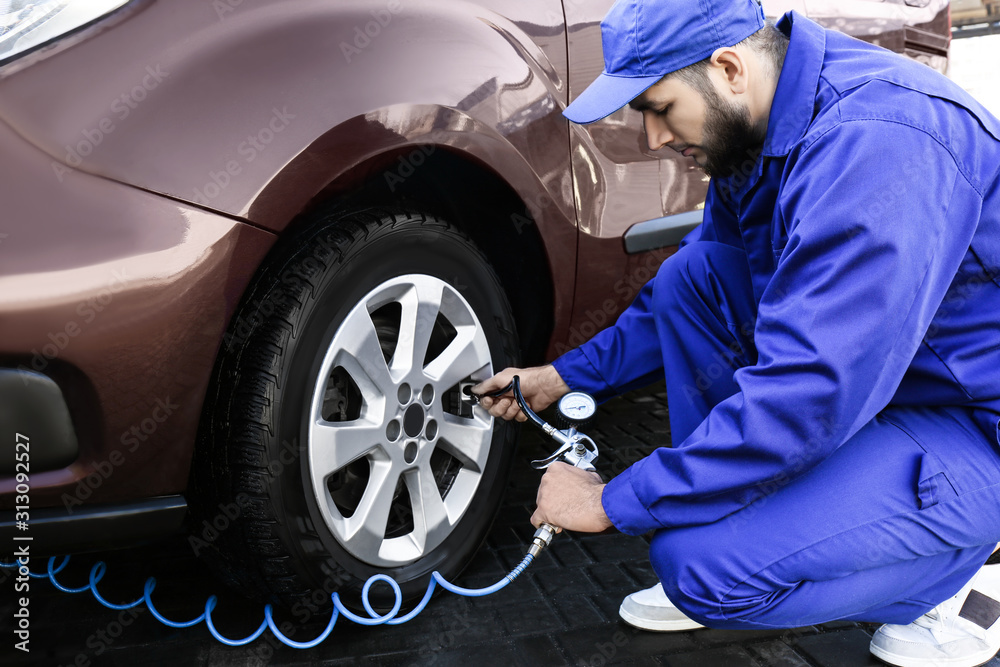 Mechanic checking tire air pressure at car service Mechanic checking tire air pressure at car service