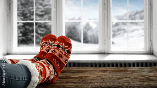 Woman legs and woolen winter socks.Blurred background of winter window. 