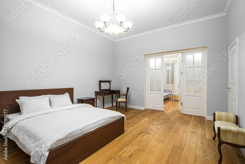 Modern interior in light tones. Bedroom with wooden furniture. White door.