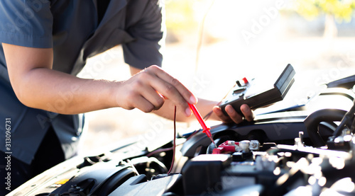 Auto repair technician has inspected the condition of the engine using ammeter  Car repair service concept.