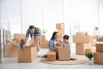 Happy family having fun while unpacking moving boxes at their new home