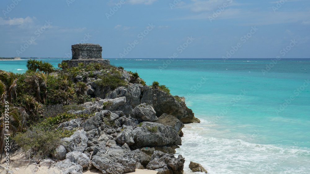 Mayan ruins tower over the coast of Caribbean sea in Tulum. It is the site of a pre-Columbian Mayan walled city serving as a major port for Coba city in Mexico.  