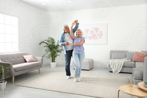 Happy mature couple dancing together in living room © New Africa