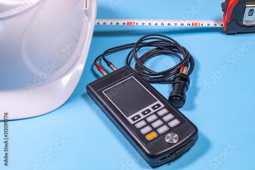 Canvas-taulu White hardhat, ultrasonic measurement device and a tape-line illustrating non destructive testing procedures (ndt)