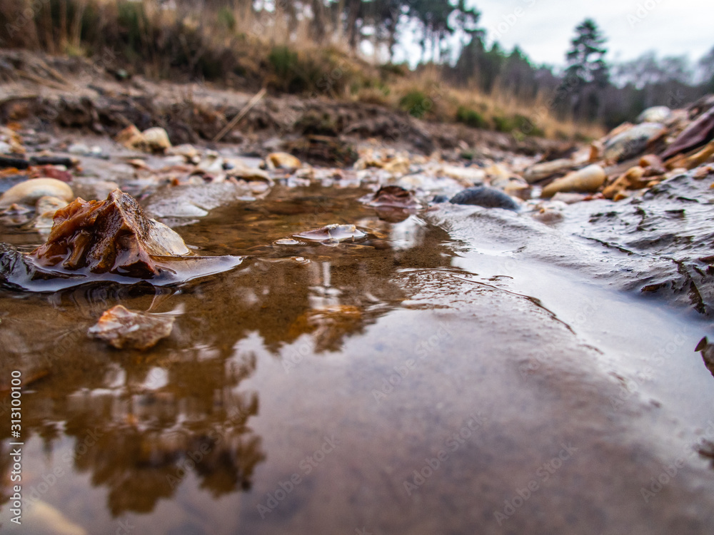 Low level view of puddle water in gully with stones Low level view of puddle water in gully with stones