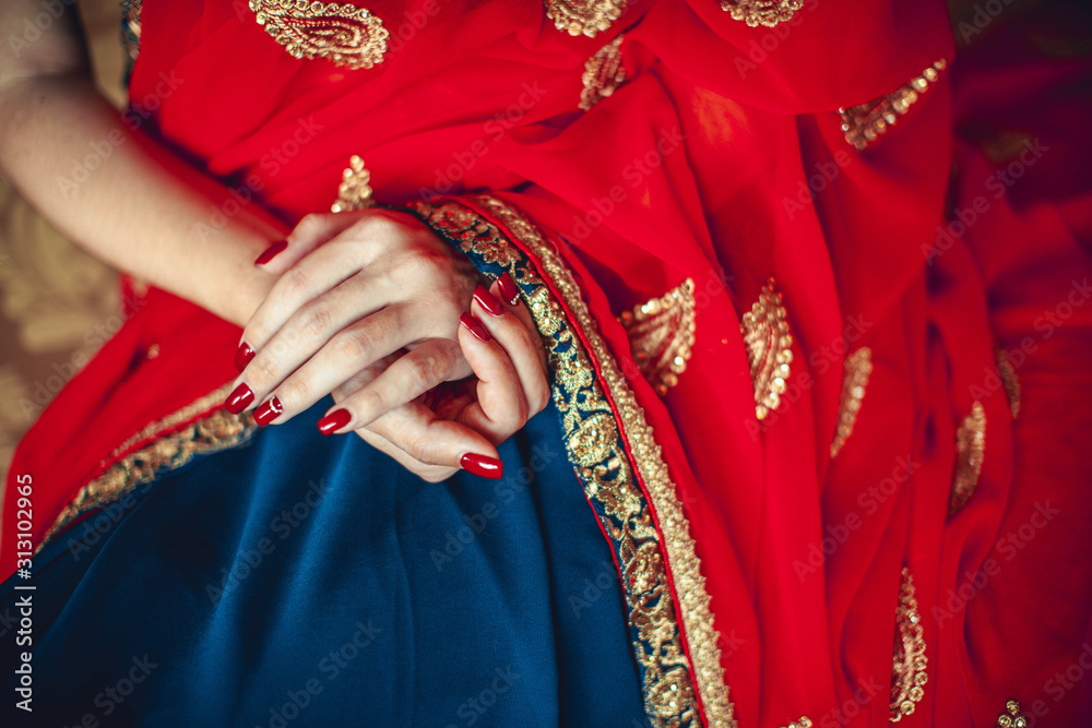 hands with red manicure on a red-blue sari