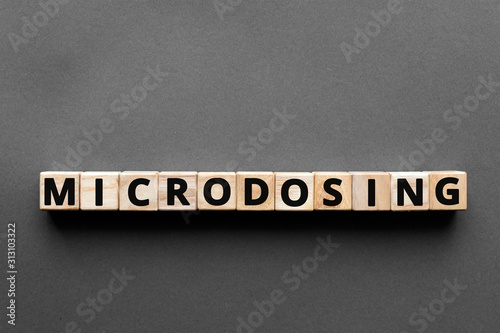 Microdosing - word from wooden blocks with letters, microdosing concept, top view gray background