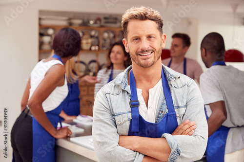 Portrait Of Smiling Mature Man Wearing Apron Taking Part In Cookery Class In Kitchen