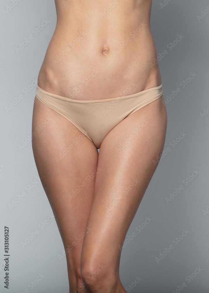 Woman in beige panties on a gray background Woman in beige panties on a gray background