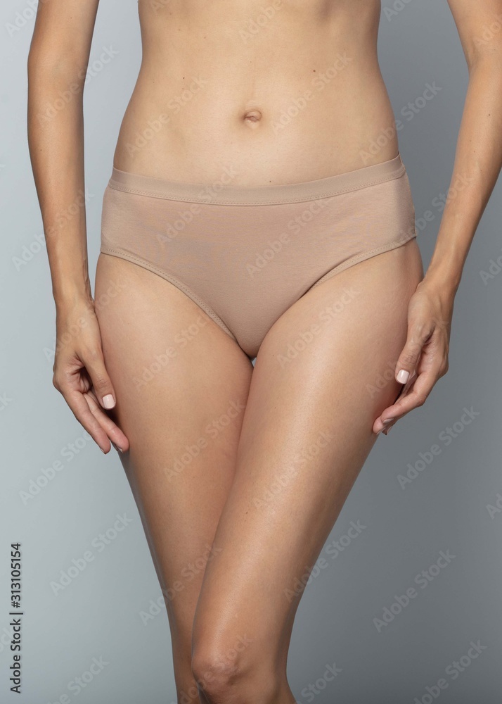 Woman in beige panties on a gray background Woman in beige panties on a gray background