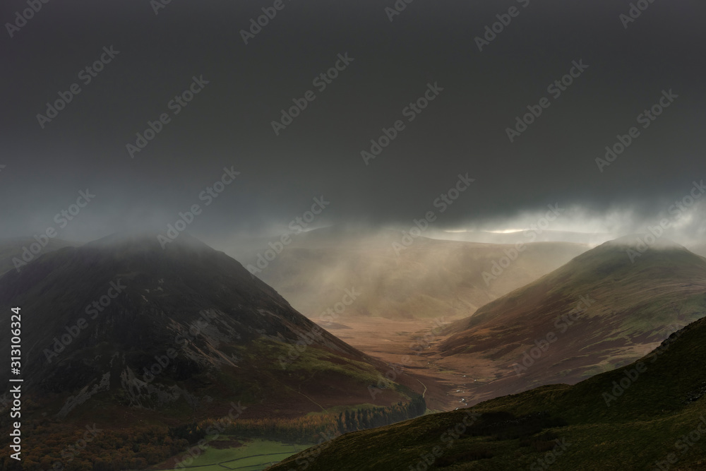 Stunning Autumn Fall landscape image of rain in valley in Lake District creating majestic lighting conditions