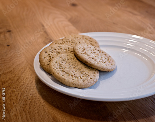 Digestive sweetmeal biscuits on white plate placed on wooden table. photo