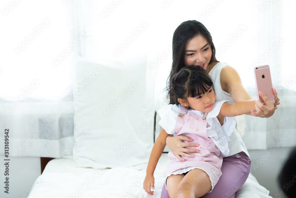 beautiful mother and her daughter making a selfie using smart phone and smiling beautiful mother and her daughter making a selfie using smart phone and smiling