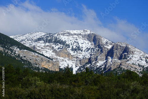 Winter photo of mount Parnitha covered with slight snow and deep blue cloudy sky on a sunny morning