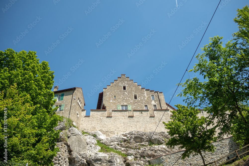 Stone medieval europe style building with green trees on clear blue sky background with copy space