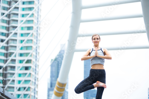 Caucasian woman wearing sportswear practicing yoga in the city