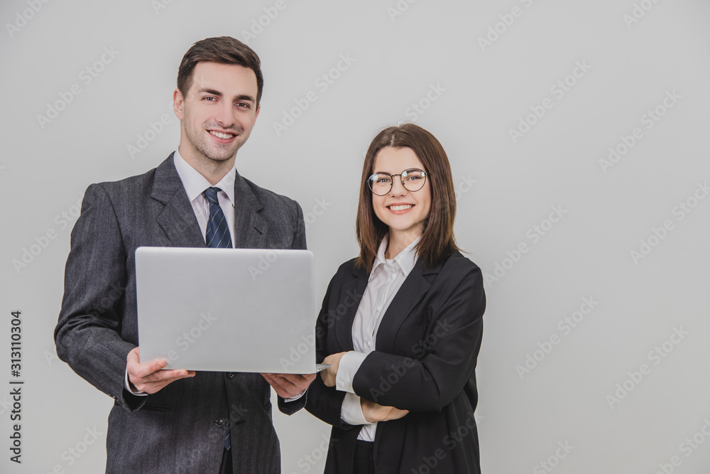 Business partners standing, checking data in the laptop, smiling happily. Woman is standing, her hands folded. Business partners standing, checking data in the laptop, smiling happily. Woman is standing, her hands folded.