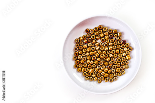 Round golden beads designed for making jewelry shot large on a white background.