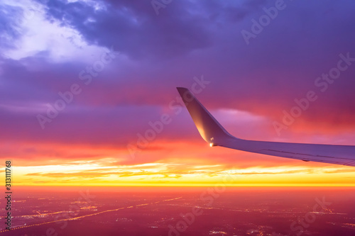 Wing of the plane lit by the sunset on a background of sky.