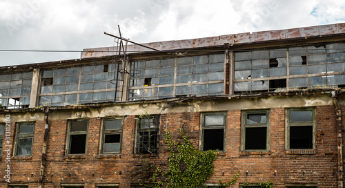 abandoned factory warehouse with broken windows and covered in green ivy plant