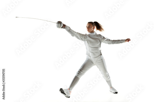 Champion. Teen girl in fencing costume with sword in hand isolated on white background. Young female model practicing and training in motion, action. Copyspace. Sport, youth, healthy lifestyle.