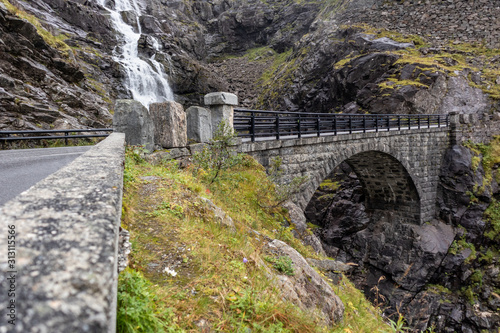 Stone bridge and waterfall on Trolls Path Trollstigen or Trollstigveien scenic mountain road in Norway Europe. Tourist route.