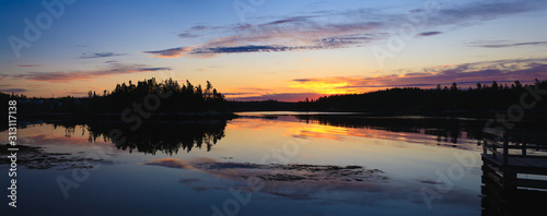 Fototapeta Naklejka Na Ścianę i Meble -  Daybreak reflections on a calm lake. Wide format image.