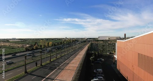 Aerial view over commercial area in the suburbs of Barcelona, Spain, showing a large mall, and highway roads, a bridge and fields in this rural background