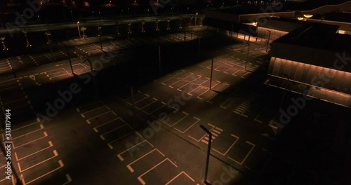 Aerial view over commercial area in the suburbs of Barcelona, Spain, showing parking lots by night, lit by street lights, near a large mall without any visitor