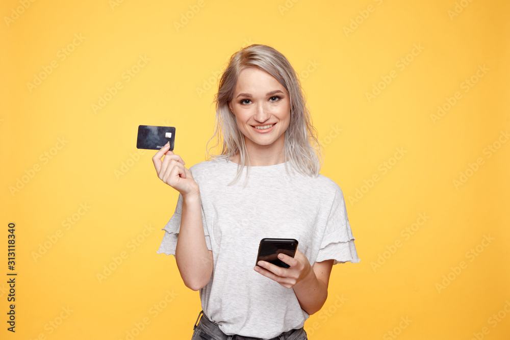 Smiling girl holding phone and credit card. Shopping online Smiling girl holding phone and credit card. Shopping online