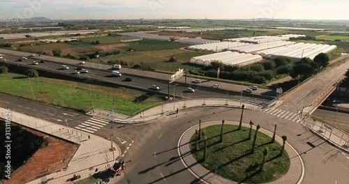 Aerial view over commercial area in the suburbs of Barcelona, Spain, showing highway roads, a roundabout and agriculture installations in the rural background