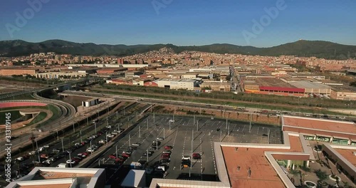 Aerial view over commercial area in the suburbs of Barcelona, Spain, showing a large mall, parking lots, highway roads, industrial sites and residential buildings in the suburbs
