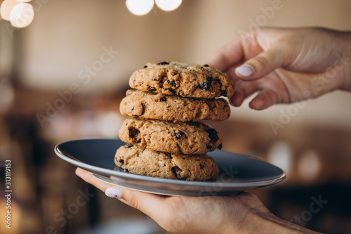 Pile of golden brown homemade oatmeal cookies on dark table background. High tower of tasty peanut oatcakes, healthy sweet home-baked products, selective focus, copy space