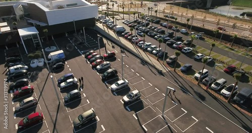Aerial view over commercial area in the suburbs of Barcelona, Spain, showing parking lots near a large mall, with people walking to their car after shopping