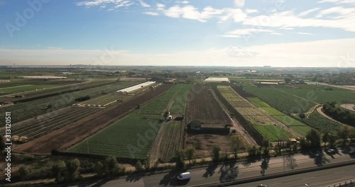 Aerial view over commercial area in the suburbs of Barcelona, Spain, showing agriculture parcels near a highway with a nice blue sky in this rural scenery